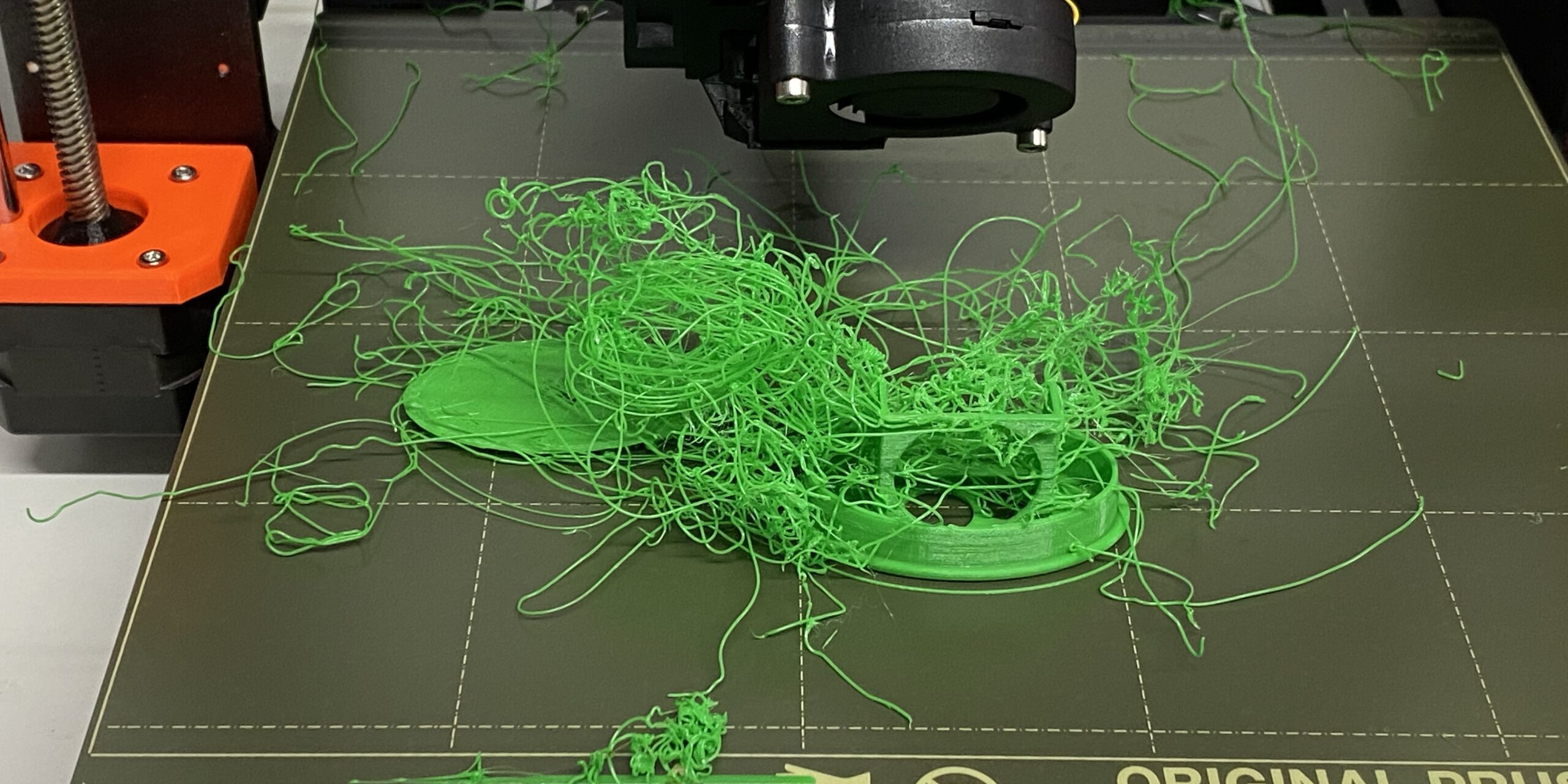 A failed 3D print showing filament spaghetti tangled on the print bed